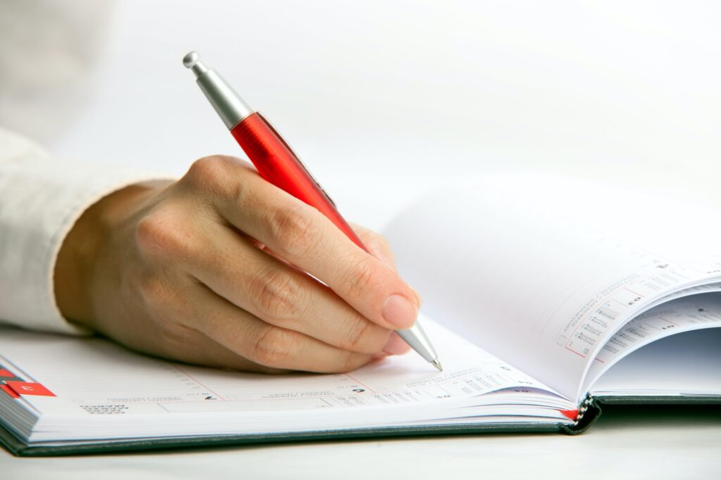 Closeup view of a businesswoman writing in a datebook