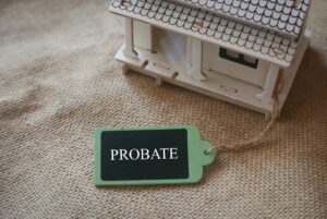 A toy wooden house on a rugs with a wooden tag written with word Probate.