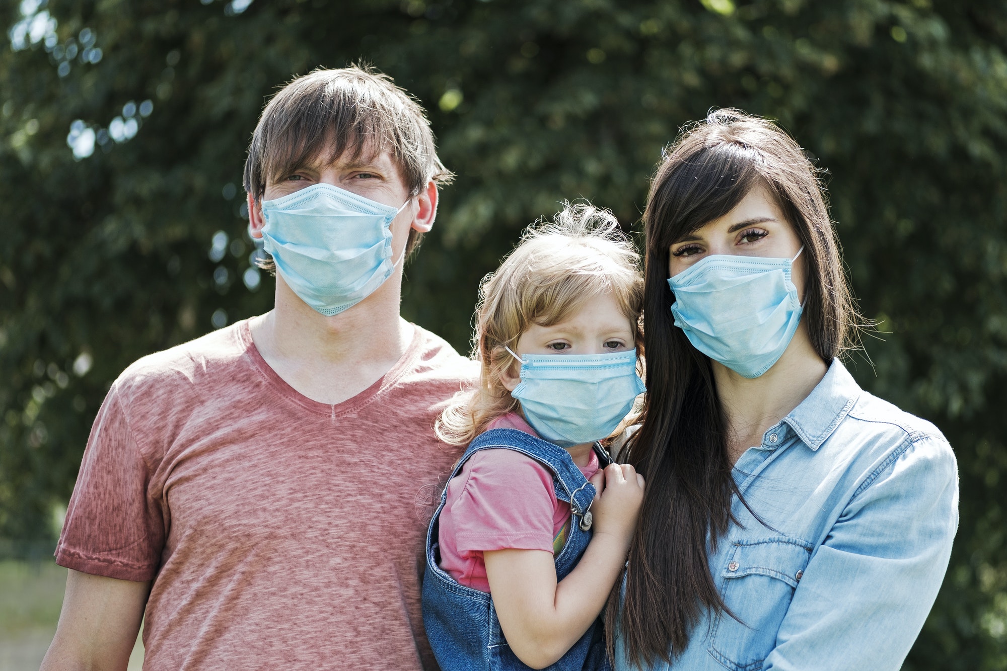 Young family with daughter wearing face masks