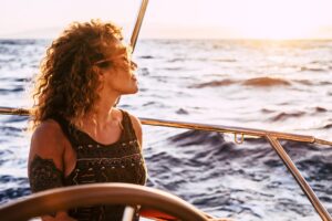 Adult rich woman enjoy luxury lifestyle traveling on sailboat yacht for summer holiday vacation