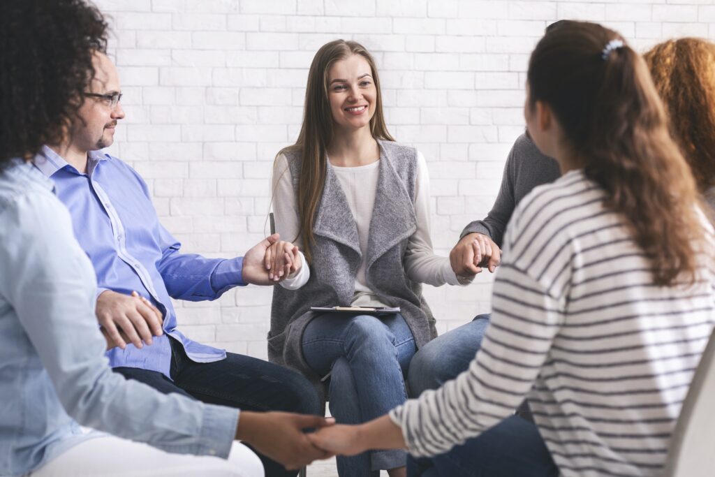 Group of addicted people holding hands, sitting in circle of trust