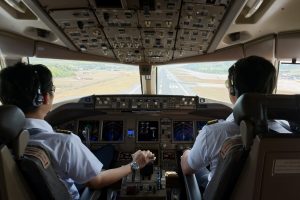 Two pilots flying the airplane with full landing configuration to the airport runway straight.