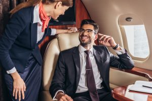 smiling businessman in suit looking at flight attendant in private plane